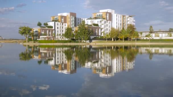 Panorama large établissant plan d'un complexe d'appartements de luxe reflétant dans un lac — Video