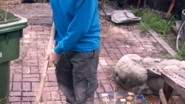 An elderly retired man struggles with a shovel to get a plant out of a pot — Stock Video