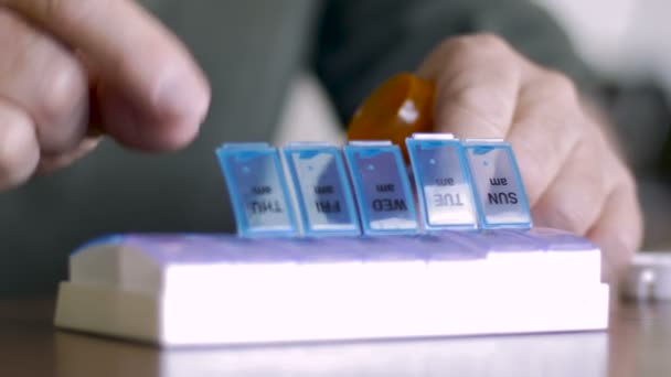 Um homem fecha seu dispensador de pílula semanal depois de preenchê-lo com seu remédio - CU — Vídeo de Stock