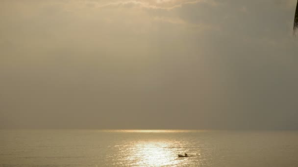 Silhouette d'un seul bateau de pêche traversant des rayons de soleil dans l'océan — Video