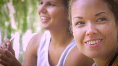 İki kadın dostluk gölün yanında bir ağaç altında buz kahve içme zevk