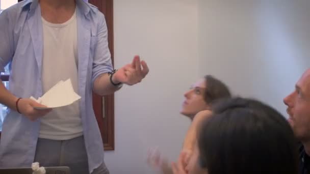 Un groupe diversifié de jeunes travaillent ensemble en se jetant du papier 