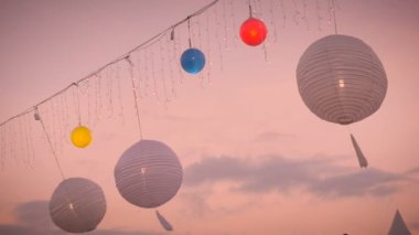 Ağır çekim, günbatımında rüzgarda beyaz ve renkli lamba fener