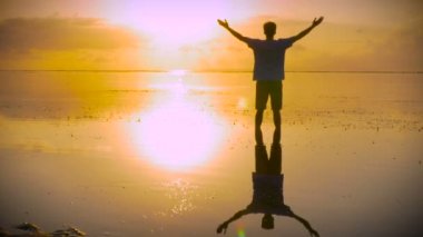 Adam sahilde güneşe doğru uzanarak lotus poz taşır