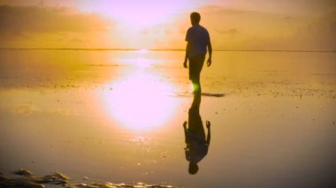 Adam ibadet poz çekip güneşe doğru uzanarak sahilde