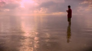 Bir adam dua kafasını yay ise sakin bir okyanusta ayakta yan görünüm