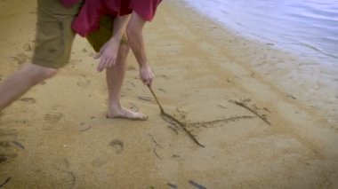 Çekici bir adam yazıyor ı Love You bir sopayla sahilde kum