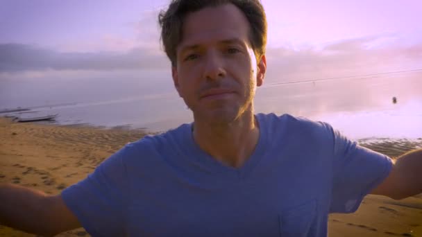 Handschuss junger Mann mittleren Alters winkt vor Kamera am Strand — Stockvideo