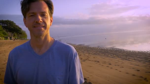 Handgehaltene Aufnahme eines Mannes mittleren Alters am Strand, der einverstanden ist und in die Kamera spricht — Stockvideo