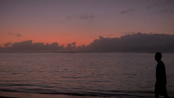 男はカラフルな早い日の出のフレームに入るし、太陽に向かって見える — ストック動画