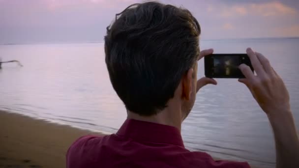 Foto de mão de um homem de meia idade tirando fotos de telefone inteligente na praia — Vídeo de Stock