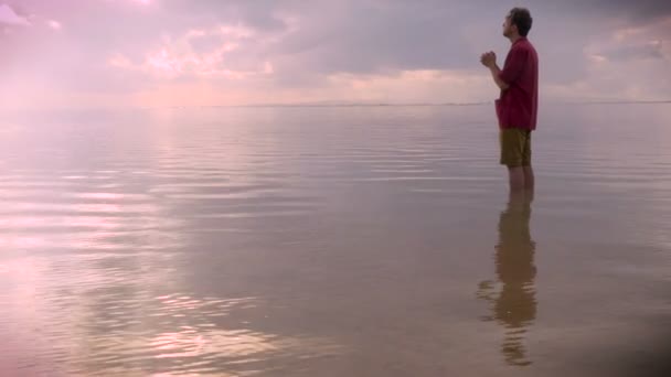 Vista laterale media di un uomo che prega in acqua durante l'alba o il tramonto — Video Stock