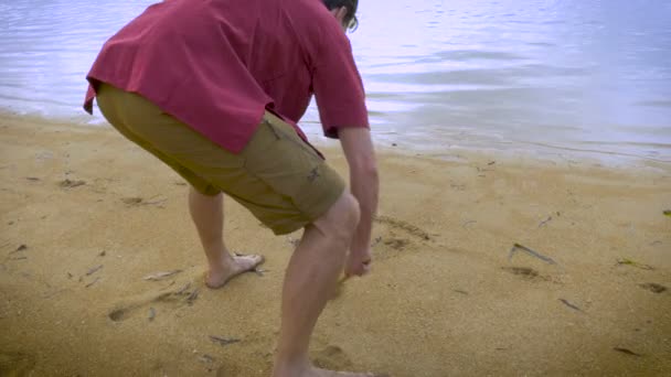 El hombre dibuja un corazón en la arena en una playa — Vídeos de Stock