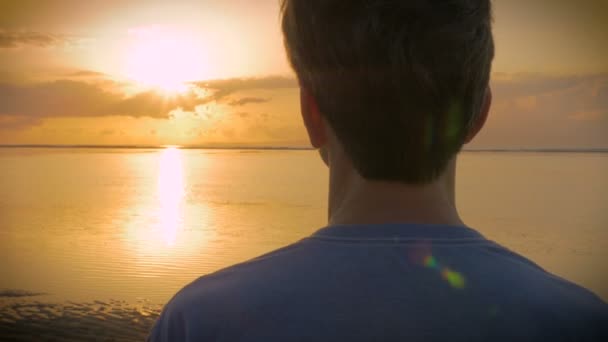 Mano sostenida sobre el hombro del hombre mirando el atardecer sobre el océano — Vídeo de stock