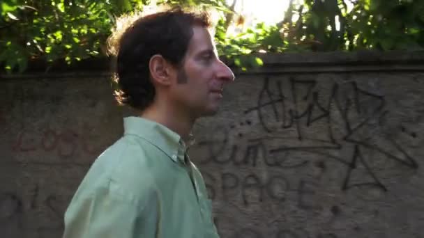 Steadicam skott av mannen gå parallellt med en vägg täckt av graffiti — Stockvideo