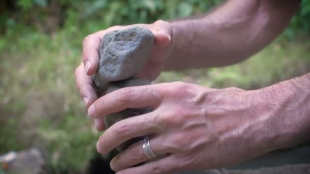 Nahaufnahme 4k Filmmaterial eines Mannes, der in der Natur Felsen balanciert — Stockvideo