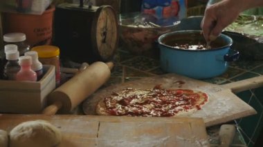 El yakın kadar peynir ve domates sosu bir ev yapımı pizza üzerine koyarak adam