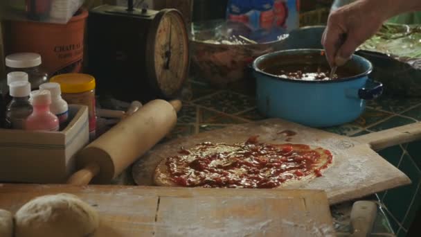 Портативный крупным планом человек кладет сыр и томатный соус на домашнюю пиццу — стоковое видео
