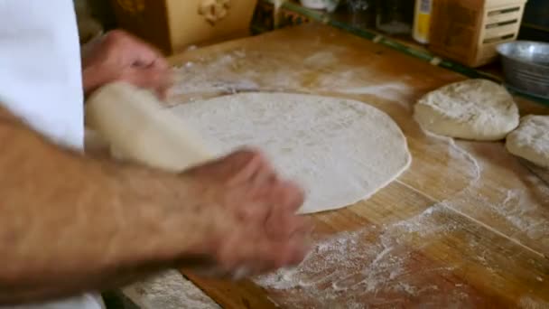 Привлекательный пожилой человек использует скалку, чтобы сделать домашнюю пиццу — стоковое видео