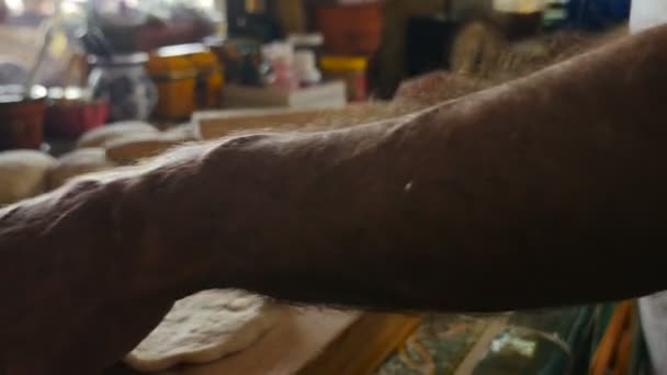 Крупним планом чоловік викидає кульку для тіста для піци на дерев'яну обробну дошку — стокове відео