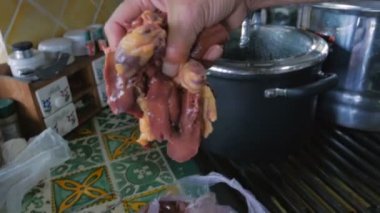 Bir adam çiğ Tavuk ciğeri bir çanta dışarı alır ve bunları bir tencereye yerleştirir.