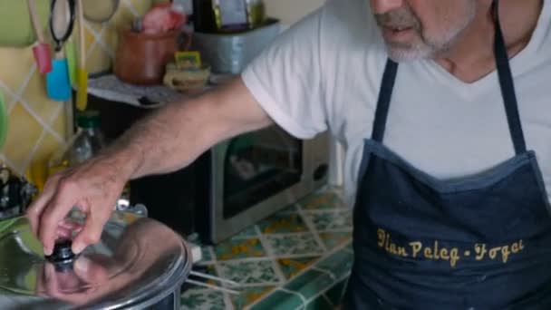 Un anciano y un hombre de mediana edad trabajan juntos cocinando en una cocina casera. — Vídeos de Stock