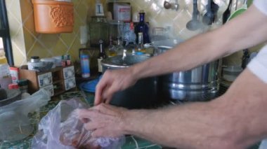 Bir adam pişmemiş Tavuk ciğeri su kaynayan bir tencereye ekler.