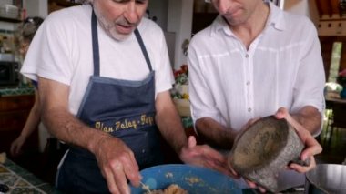 Bir orta yaşlı adam yaşlı ona nasıl yapıldığını gösterir iken bir yemek için biber ekler