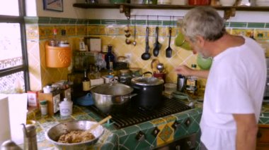 Yaşlı bir adam bir gaz sobası aydınlatma ve gıda buğulaması bir pot kontrol