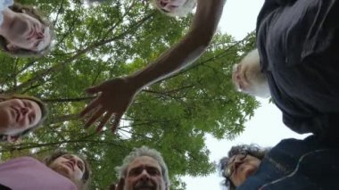 Çok nesilli bir grup insan ellerini bir daire içinde bir araya getirir.