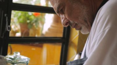 Bir bebek boomer adam yavaş hareket içinde mutfağında sert haşlanmış yumurta soyma