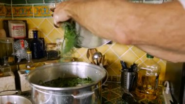 Bir fit aktif kıdemli yavaş hareket te çorba büyük bir tencerede otlar sprigs koyar