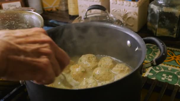 Close up van iemands hand roeren en koken van matzah bal soep op kookplaat — Stockvideo