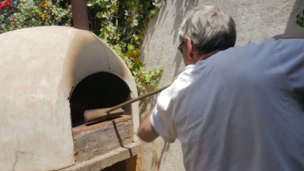 Movimiento lento de un anciano activo limpiando un horno de leña caliente — Vídeo de stock