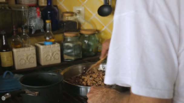 Красивый старшеклассник шевелит нарезанной печенью и луком на сковородке в замедленной съемке. — стоковое видео