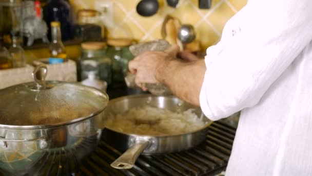 Un uomo aggiunge pepe macinato da un mortaio e pestello a una padella di cipolle grigliate. — Video Stock