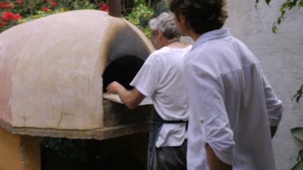 Een oudere man flipt zelfgemaakte matzah in een houtgestookte oven in slow motion — Stockvideo