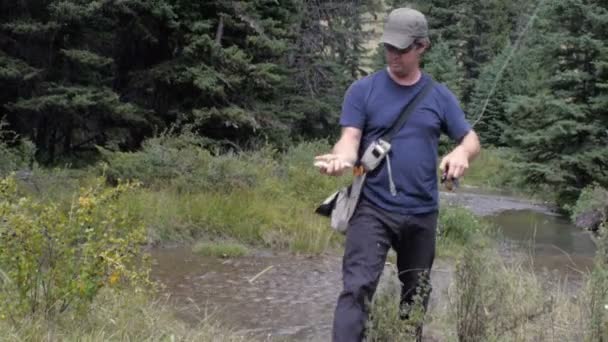 Un pêcheur montre à la caméra une truite fraîchement capturée dans le ruisseau de montagne — Video