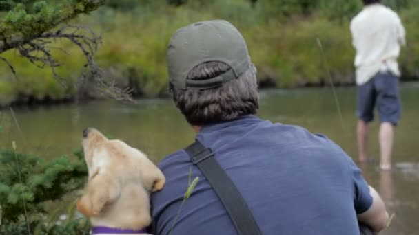 Un hombre se sienta con su perro y ve a su amigo volar peces — Vídeo de stock