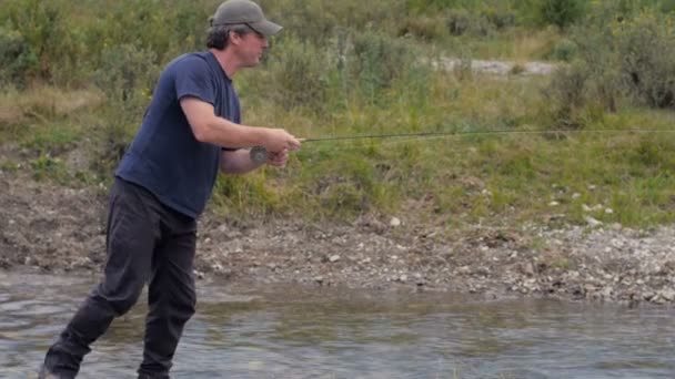 Un hombre de mediana edad la pesca con mosca y la línea se engancha — Vídeo de stock