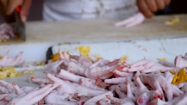 Close up de pés de frango inteiros, enquanto um homem remove as garras no fundo — Vídeo de Stock