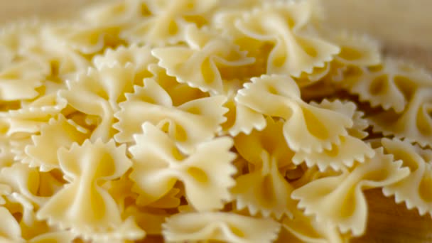 Bow tie pasta girando en una tabla de cortar de madera de cerca — Vídeos de Stock