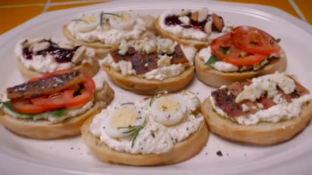 Закуски на тарелке с помидорами, сыром, беконом, яйцом, орехами, травами и джемом — стоковое видео