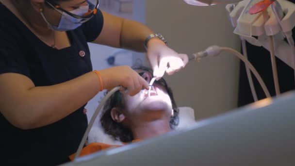 Un hombre que trabaja estrechamente con su dentista para extraer líquido de su boca — Vídeos de Stock