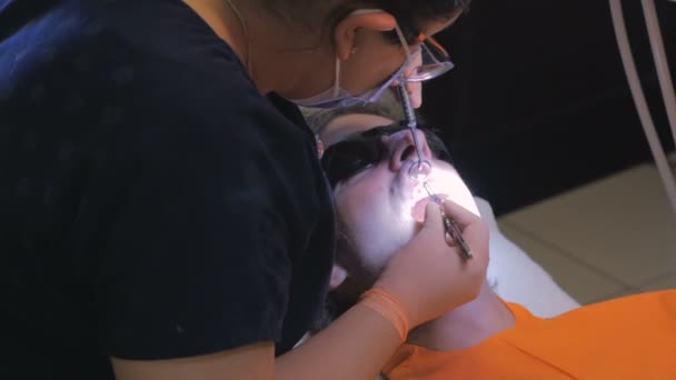 Bir adam dişlerini beyazlatılmış bir dişçi ofisinde geçiriyor — Stok video