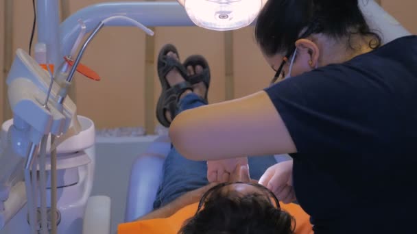 Un técnico dental usa hilo dental para los dientes de un hombre - dolly — Vídeo de stock