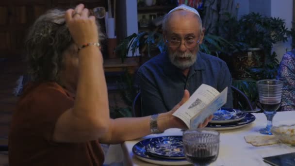 Uma mulher judia conta uma história de um livro à mesa — Vídeo de Stock