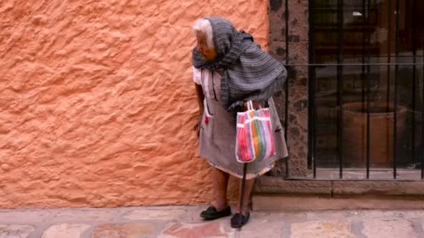 Uma velha indígena caminha com uma bengala em uma cidade histórica . — Vídeo de Stock