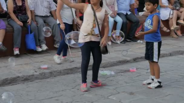 I bambini giocano con le bolle di sapone in una piazza al rallentatore — Video Stock