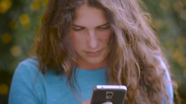 A young woman looks at her cell phone while being concerned — Stock Video